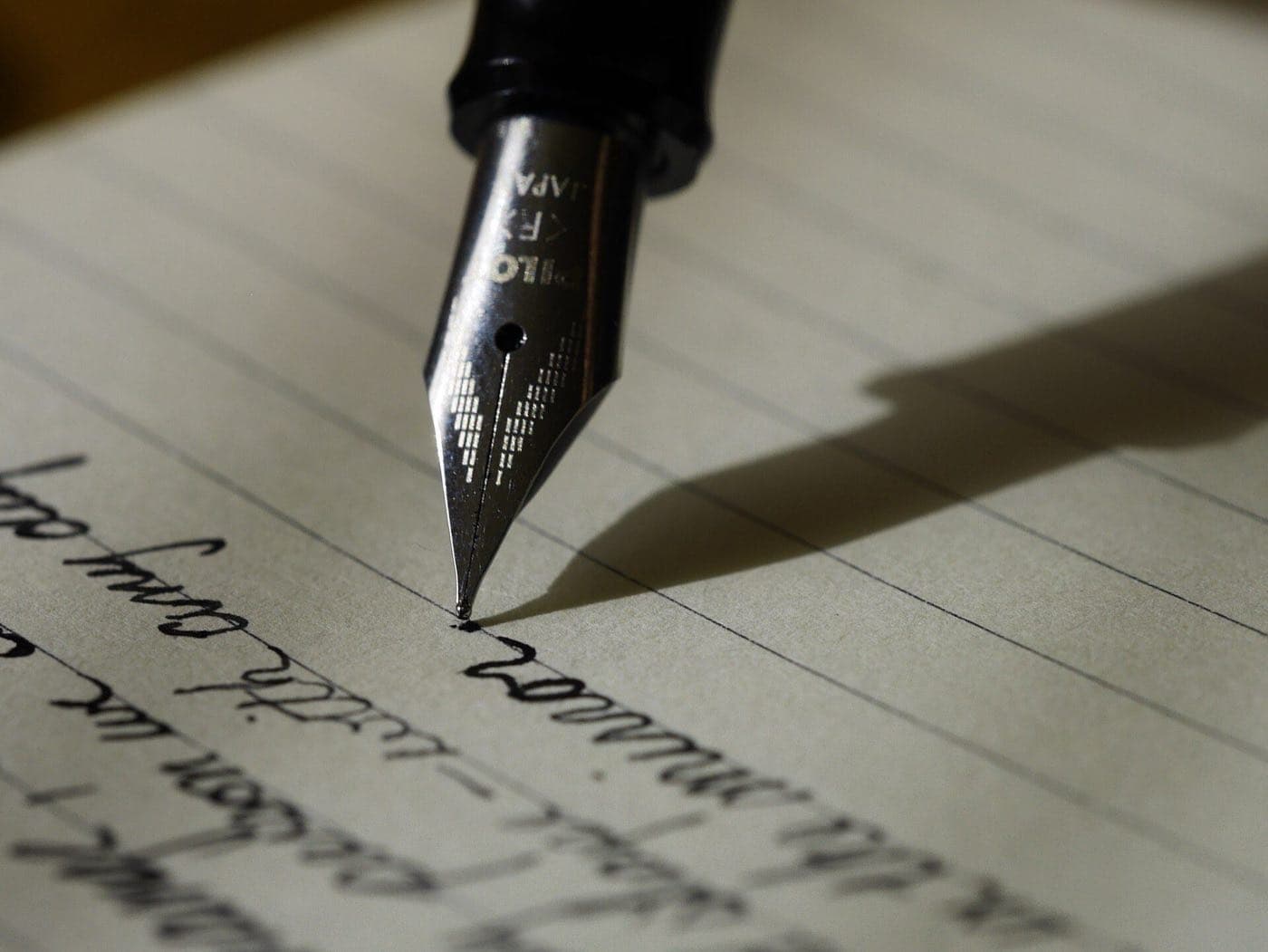 The nib of a fountain pen writing on lined paper