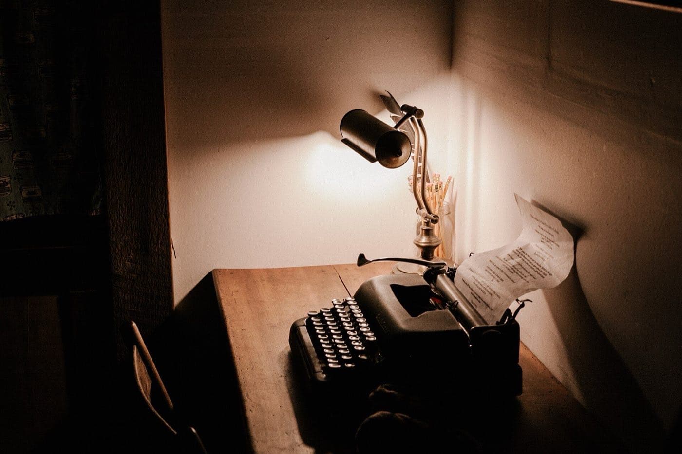 A vintage typewriter under a desk lamp with a page in the carriage