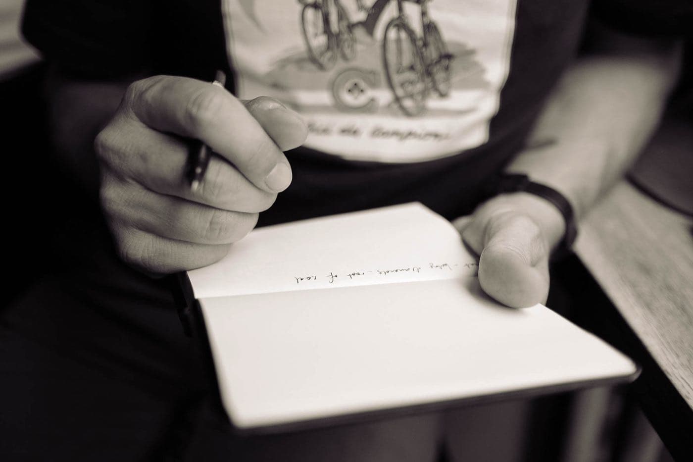 A person writing notes by hand in a small notebook